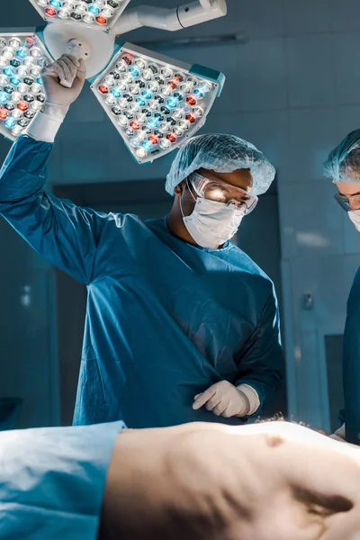 doctor and nurse in uniforms and medical caps looking at patient in operating room