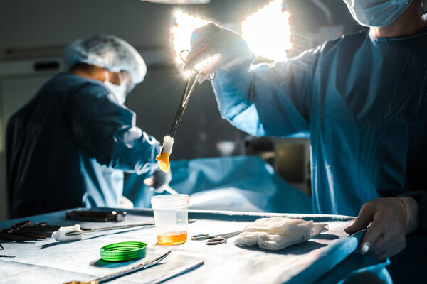 selective focus of surgeon doing operation and nurse holding tampon in operating room 