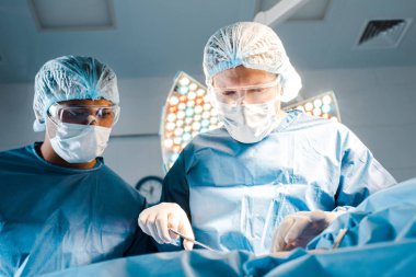 Hemşire ve cerrah üniformalı ve Tıbbi maskeler ameliyathane operasyonu yapıyor 