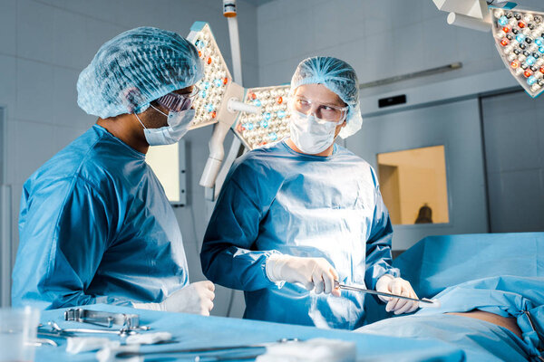 nurse and surgeon in uniforms and medical masks doing operation 