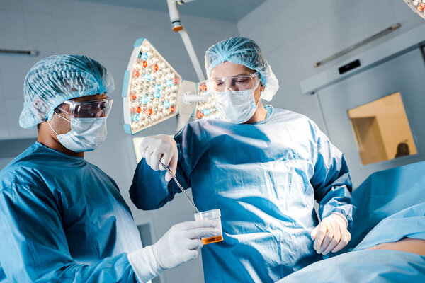 nurse and surgeon in uniforms and medical masks doing operation in operating room 