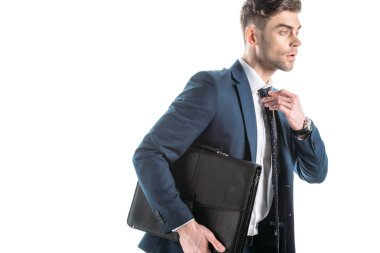 good-looking businessman holding briefcase and touching tie isolated on white clipart