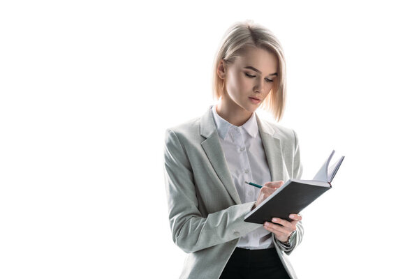 красивая, внимательная деловая женщина, пишущая в блокноте изолированы на белом
