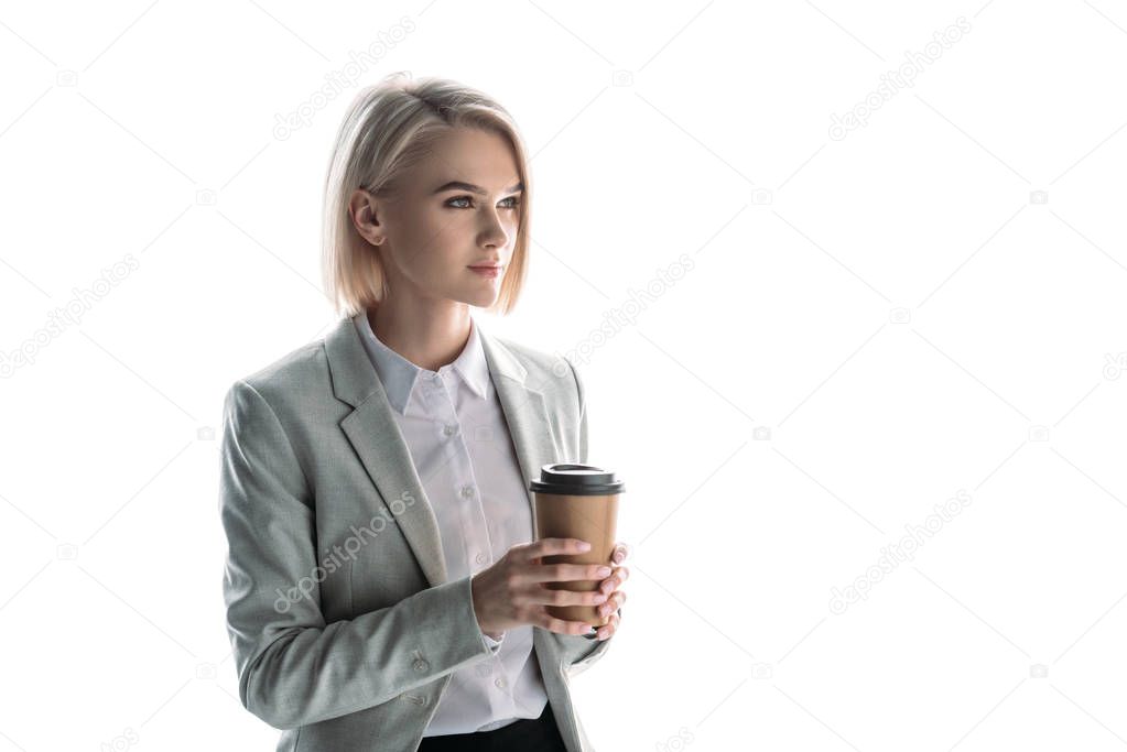 beautiful, pensive businesswoman holding paper cup and looking away isolated on white