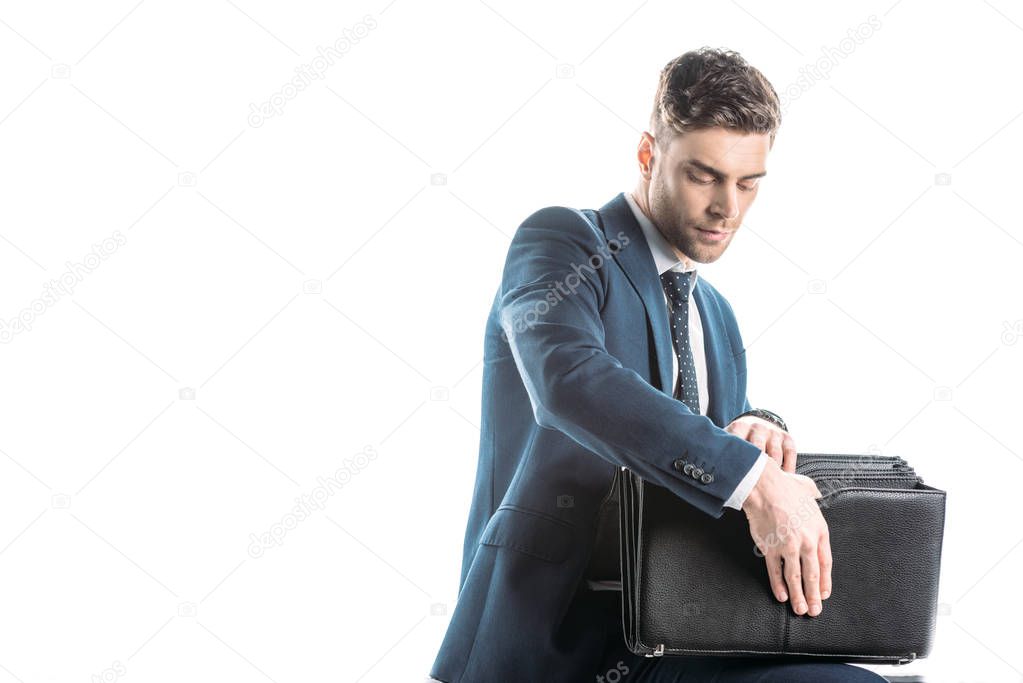 handsome, serious businessman looking into briefcase isolated on white