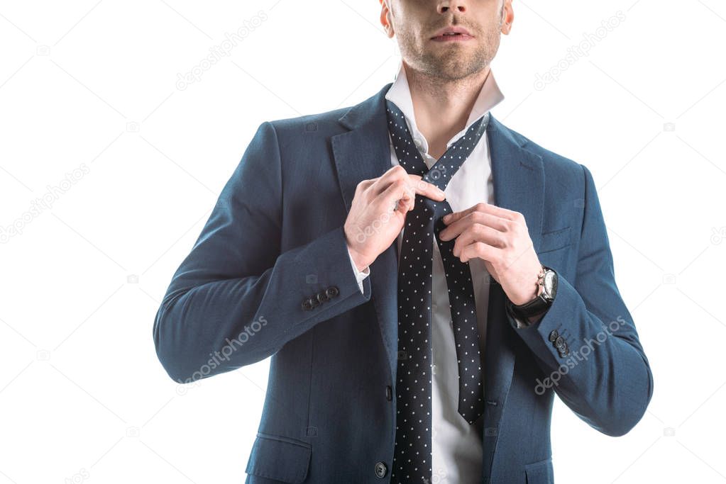 partial view of confident businessman touching tie isolated on white