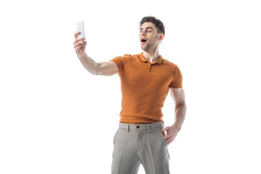 beyaz izole akıllı telefon ile selfie çeken neşeli yakışıklı adam