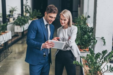 pretty businesswoman and handsome businessman using digital tablet together clipart