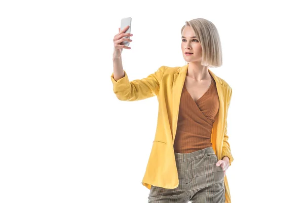 白に隔離されたスマートフォンで自分撮りを取る美しいブロンドの女性 — ストック写真