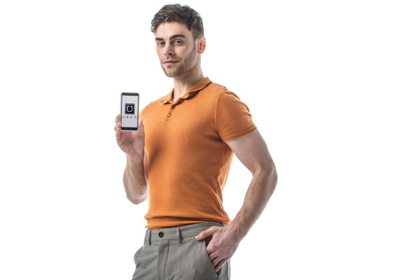 good-looking man with hand in pocket holding smartphone with uber app on screen isolated on white