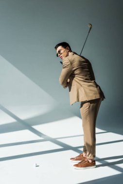 güneş ışığı ile gri üzerinde takım elbise tutarak Golf Kulübü şık karışık yarış adam