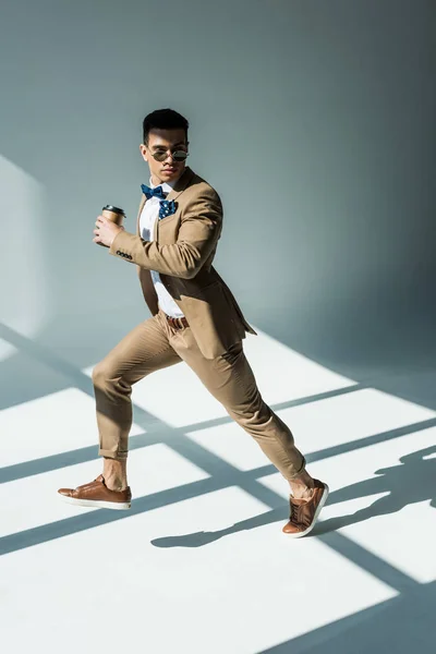 Stylish Mixed Race Man Suit Holding Coffee Jumping Grey Sunlight — Stock Photo, Image