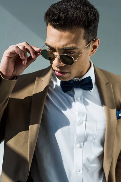 Elegante Hombre Raza Mixta Traje Pajarita Sosteniendo Gafas Sol Mientras —  Fotos de Stock