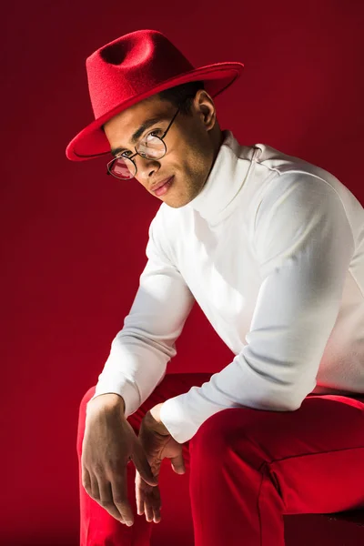Elegante Hombre Raza Mixta Sombrero Gafas Sentado Mirando Cámara Posando —  Fotos de Stock