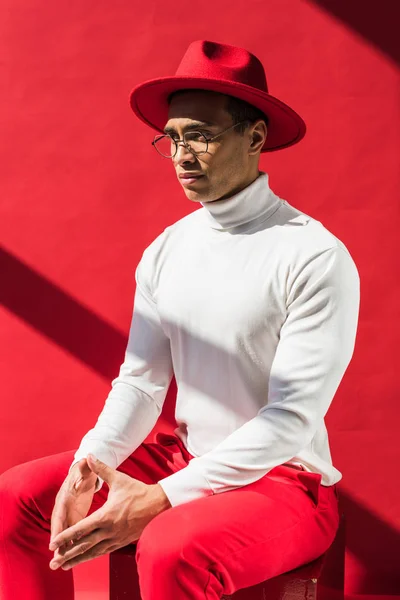 Elegante Hombre Raza Mixta Sombrero Gafas Sentado Posando Rojo —  Fotos de Stock