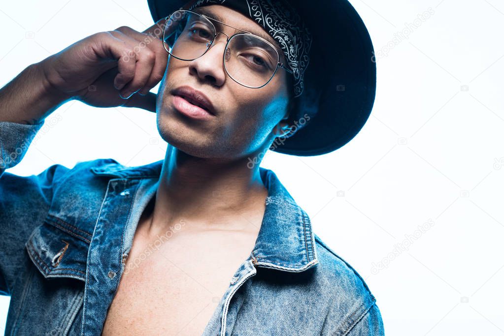 handsome stylish mixed race man in denim and glasses looking at camera isolated on white