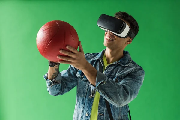 stock image mixed race man in virtual reality headset holding basketball and smiling on green screen