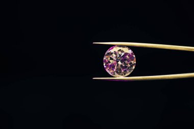 colorful pure sparkling diamond in tweezers isolated on black clipart
