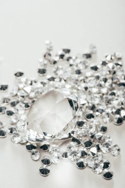selective focus of transparent pure big diamond among small on white background clipart