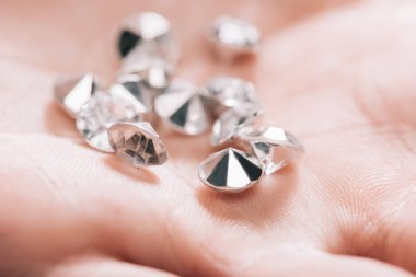 close up of shiny small pure diamonds in hand clipart