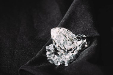küçük siyah dokulu parlak kumaş üzerine arasında köpüklü büyük elmas 