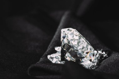 sparkling pure big diamond among small on black textured shiny cloth  clipart