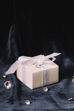 engagement ring on gift box near shiny diamonds on blue cloth clipart