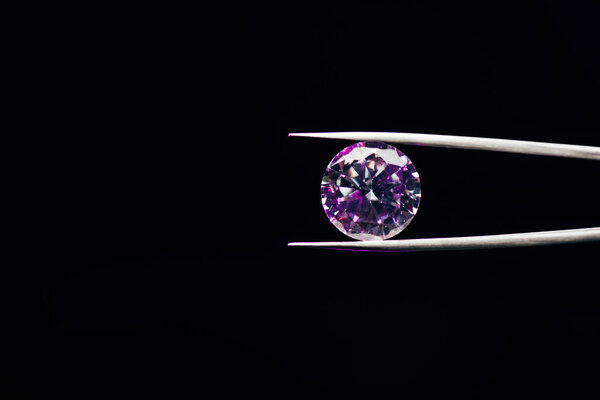 красочный фиолетовый сверкающий бриллиант в пинцетах, изолированных на черном
