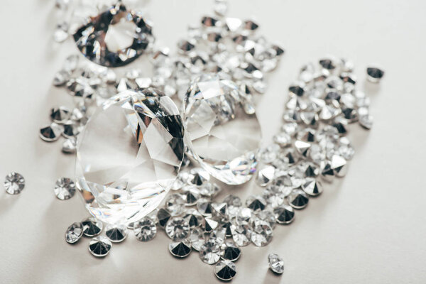 селективный фокус прозрачных чистых больших алмазов среди мелких на белом фоне

