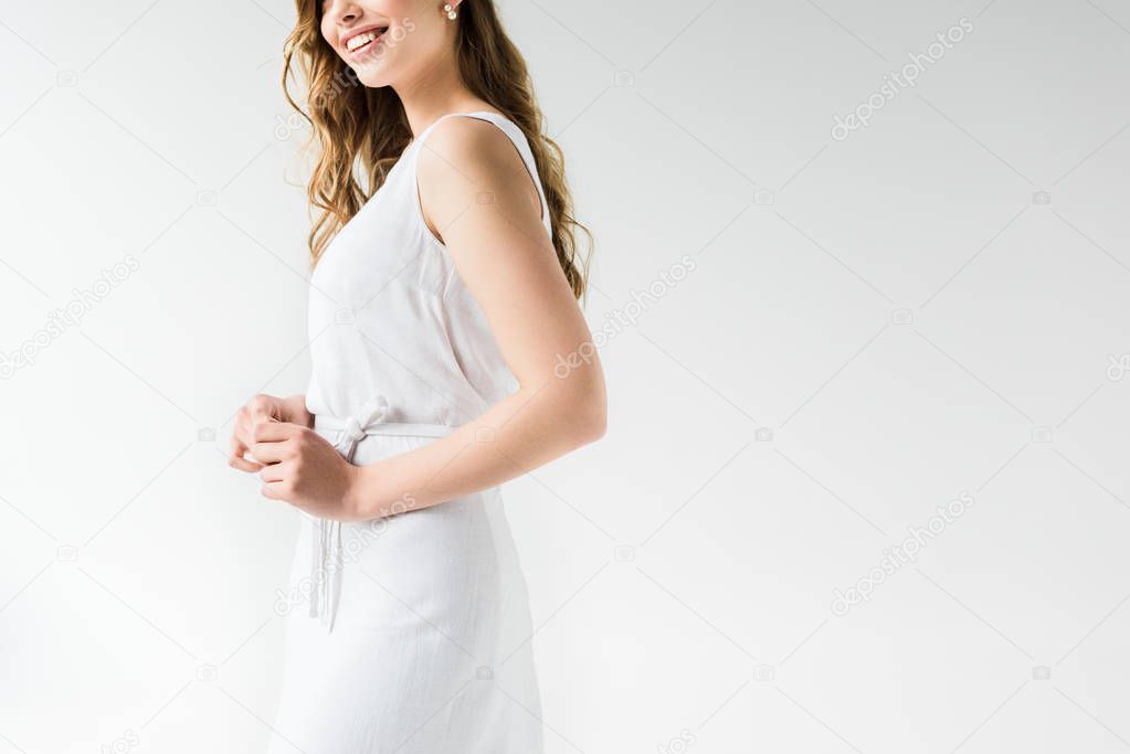 cropped view of cheerful girl in dress smiling on white