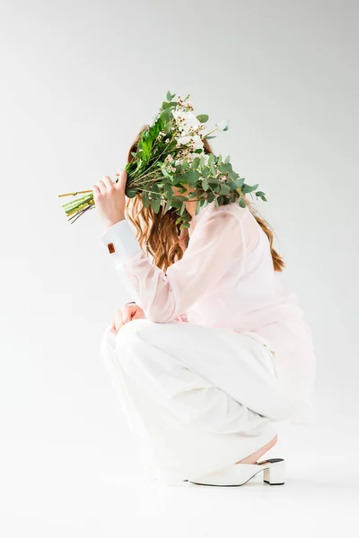Chica Cubriendo Cara Con Flores Con Hojas Eucalipto Verde Mientras — Foto de Stock