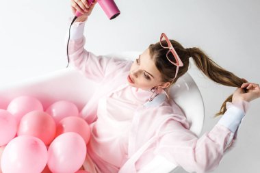 güzel kız saç beyaz üzerine pembe hava Balonlu küvet içinde yatan ise kurutma makinesi kullanarak havai görünümü 