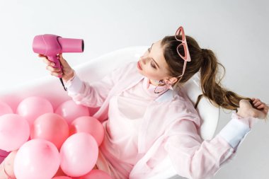 beyaz üzerine pembe hava Balonlu küvet içinde yatan fön kullanan kız havai görünümü 