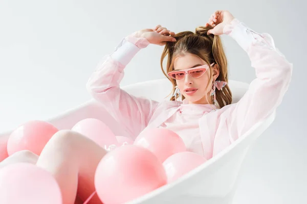 Stylowe Młoda Kobieta Okulary Leżąc Wannie Różowy Balony Dotykając Włosów — Zdjęcie stockowe