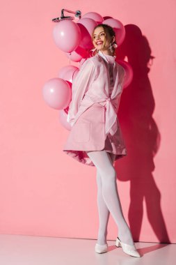 hava balonları duran pembe üzerinde tutan mutlu kadın