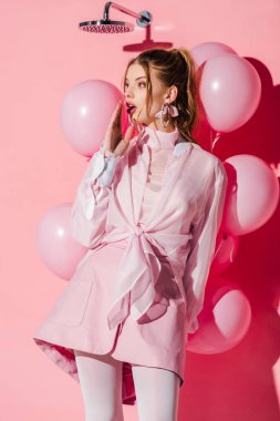 hava balonları duran pembe üzerinde tutan sürpriz kadın