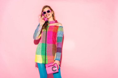 güneş gözlüğü ve Damalı elbise pembe retro telefonla konuşurken neşeli genç kadın