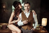 sexy Frau in schwarzen Dessous sitzt auf Holztisch und flirtet mit Detektiv im Büro