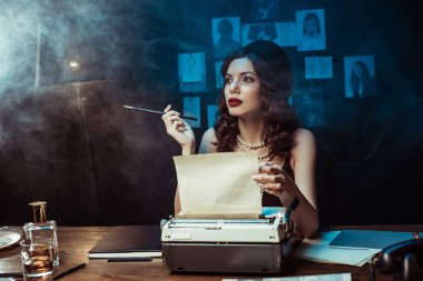 Karanlık ofiste daktilo kullanarak ağız parçası ile Pensive kadın