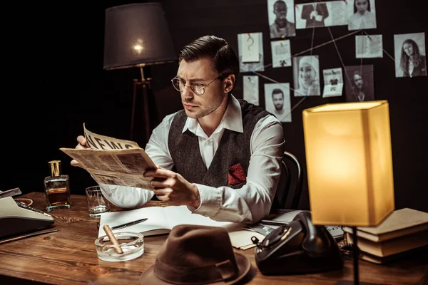 メガネでの集中探偵ダークオフィスで新聞を読む — ストック写真