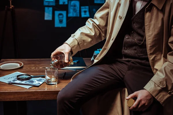 Gedeeltelijke Weergave Van Detective Gieten Cognac Glas Zittend Tafel — Stockfoto