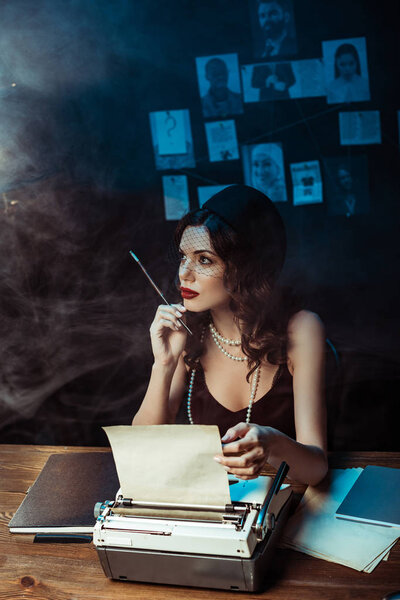 Страшная женщина с мундштук с пишущей машинкой в темном офисе
