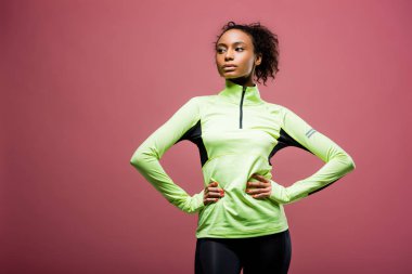 güzel Afro-Amerikan sporcumuz akimbo poz pink izole elle parça ceketli