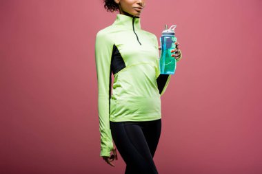 Kısmi izole kahverengi üzerine spor şişe ile parça ceketli Afro-Amerikan sporcumuz görünümünü