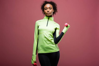 Kameraya bakarak ve izole kahverengi üzerine dumbbells ile eğitim güzel Afro-Amerikan sporcumuz