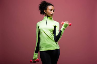 güzel Afro-Amerikan sporcumuz izole kahverengi üzerine dumbbells ile eğitim