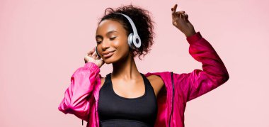 müzik dinleme ve pembe izole el hareketi Kulaklığımda güzel Afro-Amerikan sporcumuz panoramik çekim