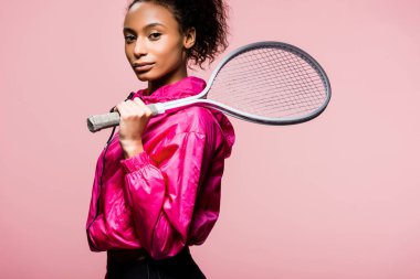 Tenis raketi ile poz kameraya bakıyor güzel Afro-Amerikan sporcumuz pink izole