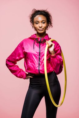 Kameraya bakarak ve hula hoop pink izole tutan güzel Afro-Amerikan sporcumuz
