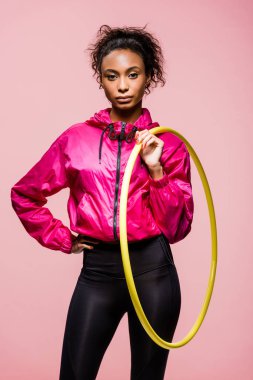 Kameraya bakarak ve hula hoop pink izole tutan güzel Afro-Amerikan sporcumuz